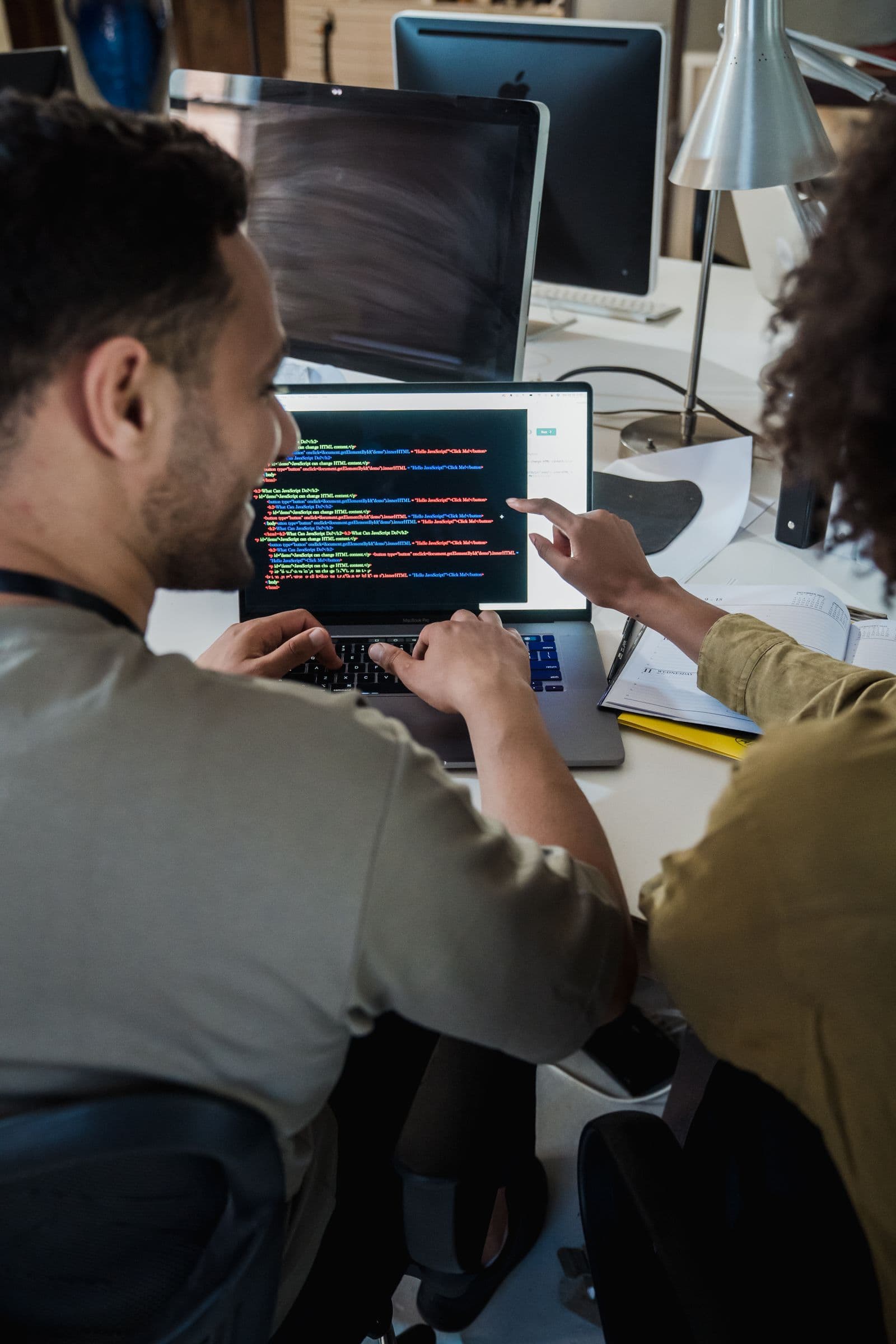 Two developers, a woman and a man, reviewing code together on a laptop