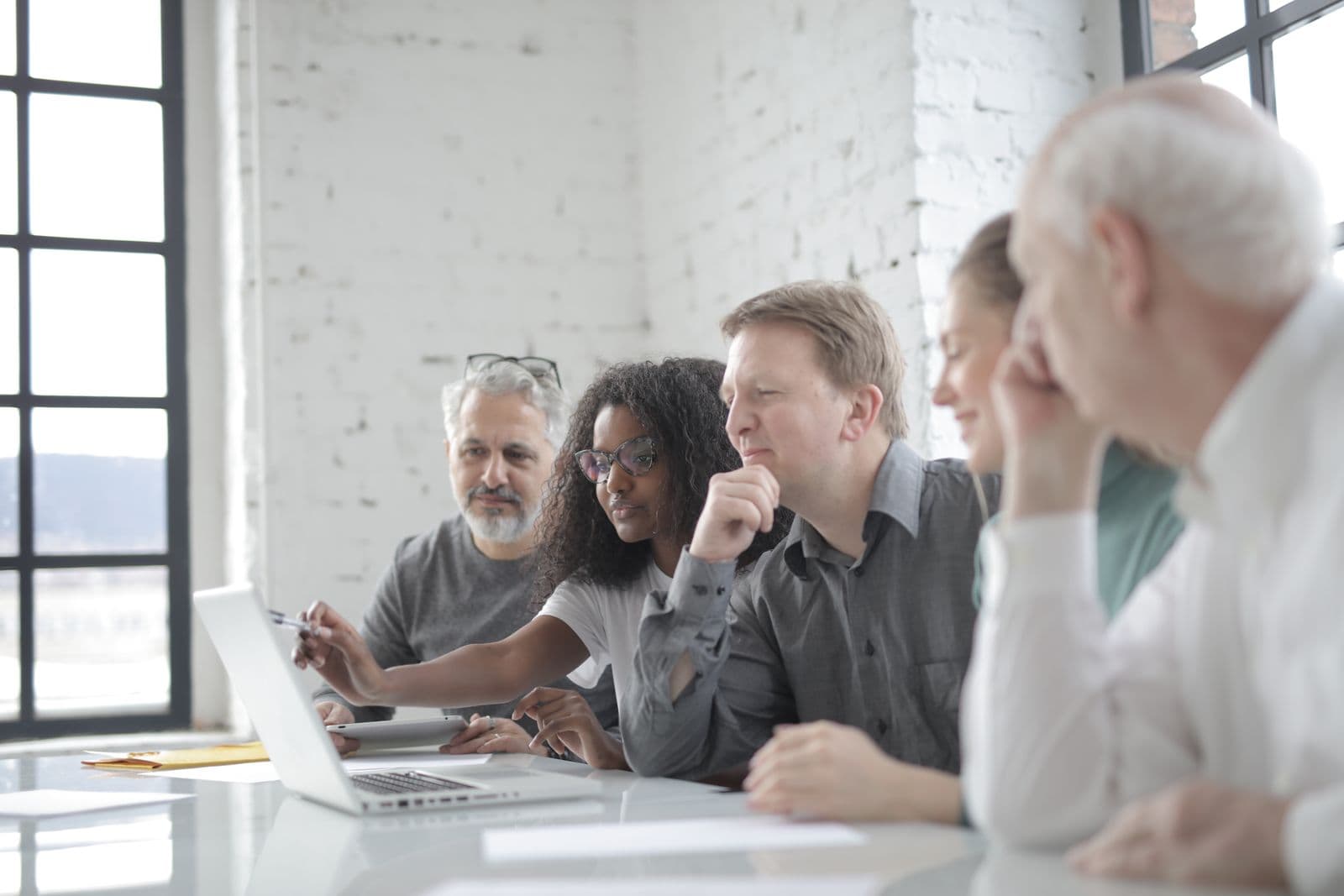 A facilitator coaching colleagues through a Microsoft 365 workflow on a laptop