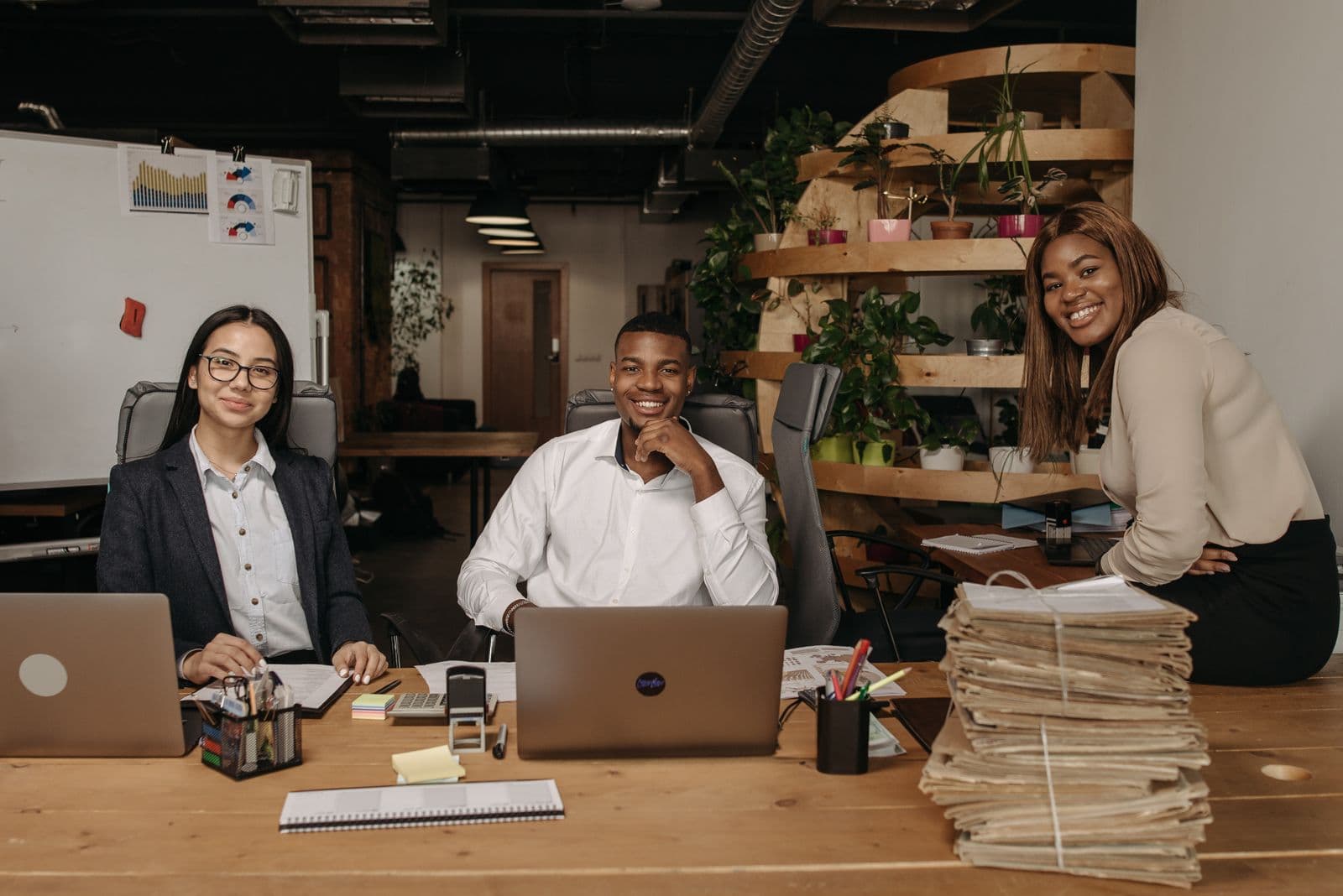 Three smiling professionals at their desks, ready to talk through a new engagement